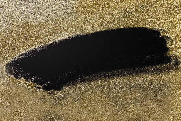 Golden glitter on a black surface, background for Christmas, new year, birthday, special occasions, with a copy space.