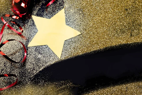 Sammansättning av gyllene glitter, stjärna och rött band på svart bakgrund för jul, nytt år, speciella tillfällen, med en kopia utrymme. — Stockfoto