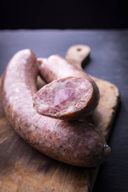 Taze, çiğ yağlı sosis ahşap bir tezgahın üzerindeki tahta kesme tahtasında..