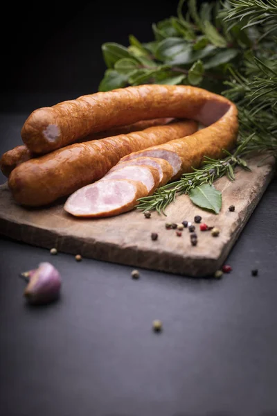 Anneaux de saucisse fumée de porc traditionnelle, champêtre, maison sur une planche à découper en bois sur un comptoir caillouteux . — Photo