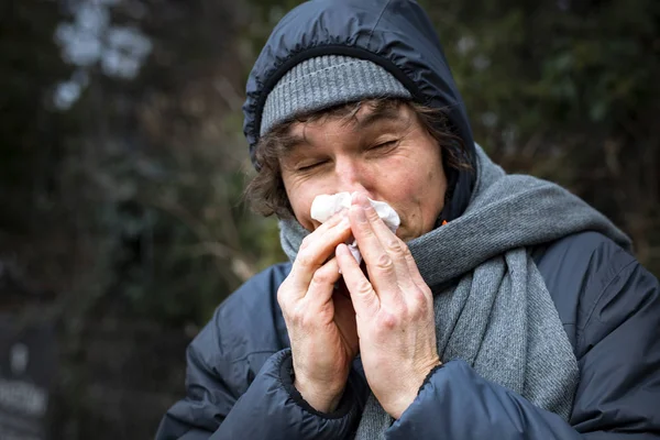 Runny nose. Sick man blowing his nose with a tissue. Infection, flu, viral diseases.
