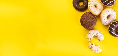 Sarı arka planda çeşitli malzemelerle donutlar. Şişman Perşembe. Çörekler.