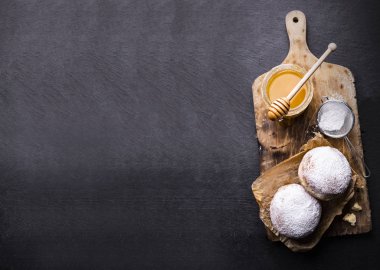 Siyah taşlı tezgahın üzerinde pudra şekerli çörekler. Tatlı hamur işleri ve fotokopi alanı ile pankart.