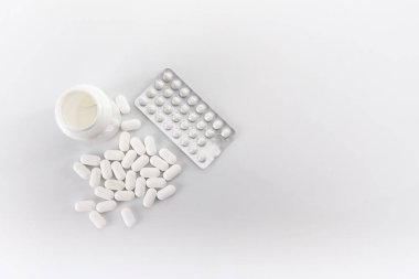 Bir paket hap, dağınık haplar ve boş ilaç şişesi, beyaz bir kutuda izole edilmiş..