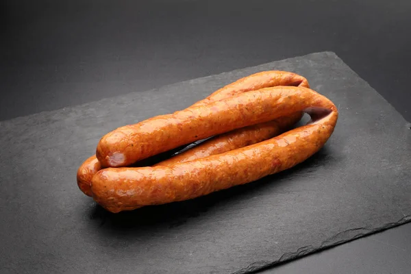 Anneaux de saucisse de porc fumée sur fond sombre . — Photo