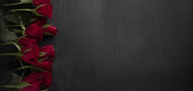 Valentines Day. Red roses on a black stony background, wide, top view with a copyspace.