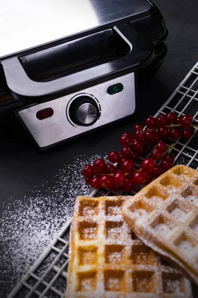 Waffles dourados com açúcar em pó e ferro waffle em uma bancada pedregosa — Fotografia de Stock