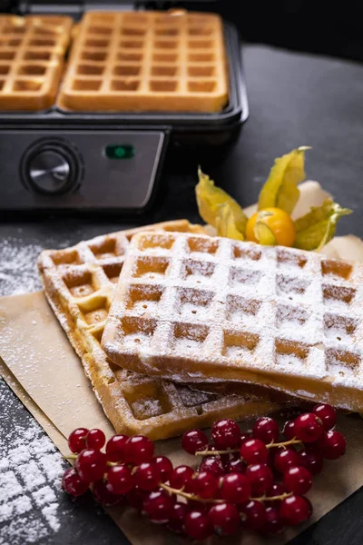 Classic golden waffles with powdered sugar and fruits in a composition on stony worktop — Stock Photo, Image