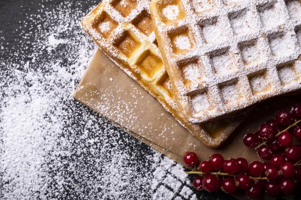 Two freshly baked waffles with powdered sugar and red currant fruits on stony worktop — Stock Photo, Image