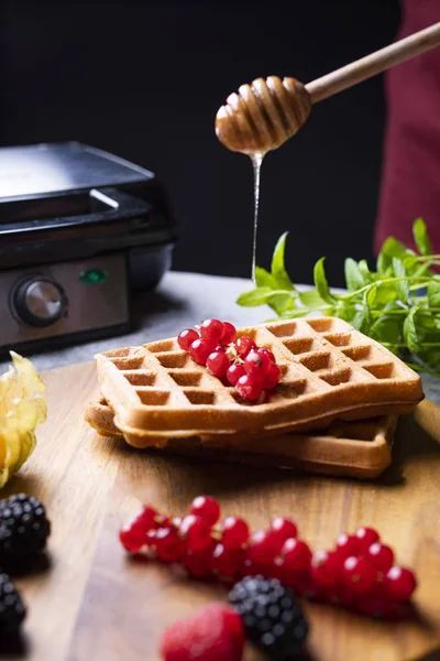 Topping golden Belgium waffles with fresh fruits and honey. — Stock Photo, Image