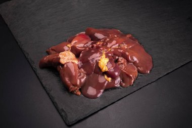 Chicken livers on a dark stony background.