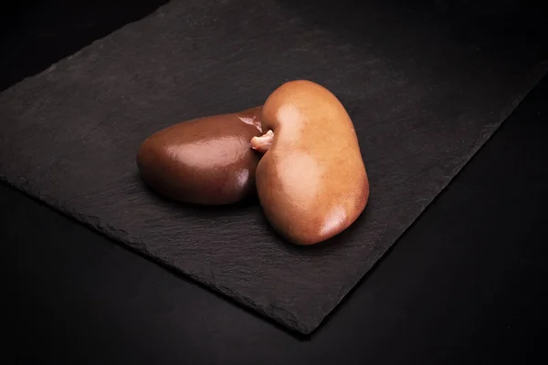 Raw pork kidneys on a black background — 스톡 사진