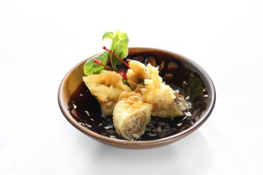 Tempura içinde kızarmış muz, badem gevreği, nane yaprakları ve üzerinde maraska kirazı, küçük, minimal stil, kahverengi bir kâsede. Beyaz arka planda izole edilmiş bir suşi restoranında doğulu bir tatlı.