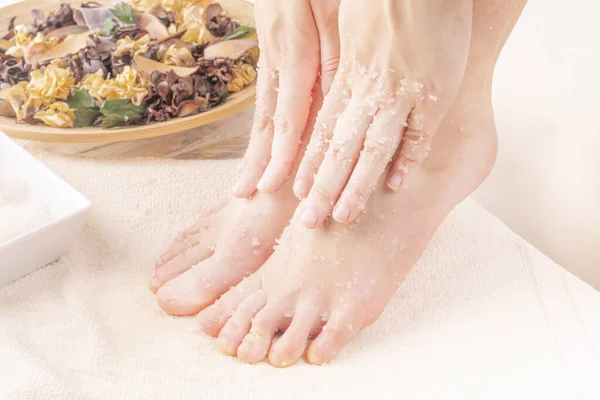 Home SPA. Young woman doing foot peeling, scrub using natural cosmetics.