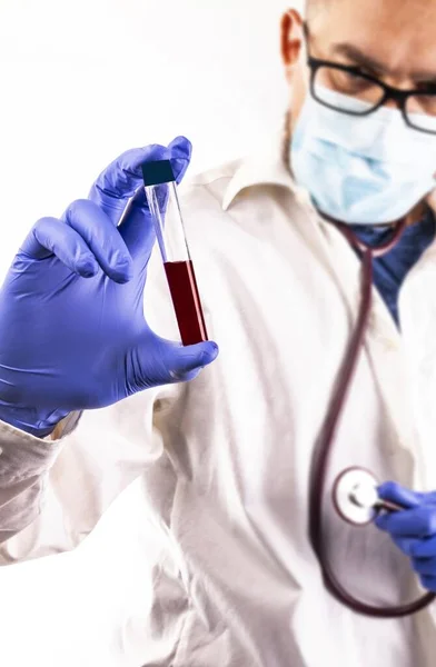 若い医師は 白い背景に 血液サンプルと試験管を保持し 医療面マスクと手袋を持つ実験室の開業医 定期的な血液検査 コロナウイルス検査 コロナ大流行 — ストック写真