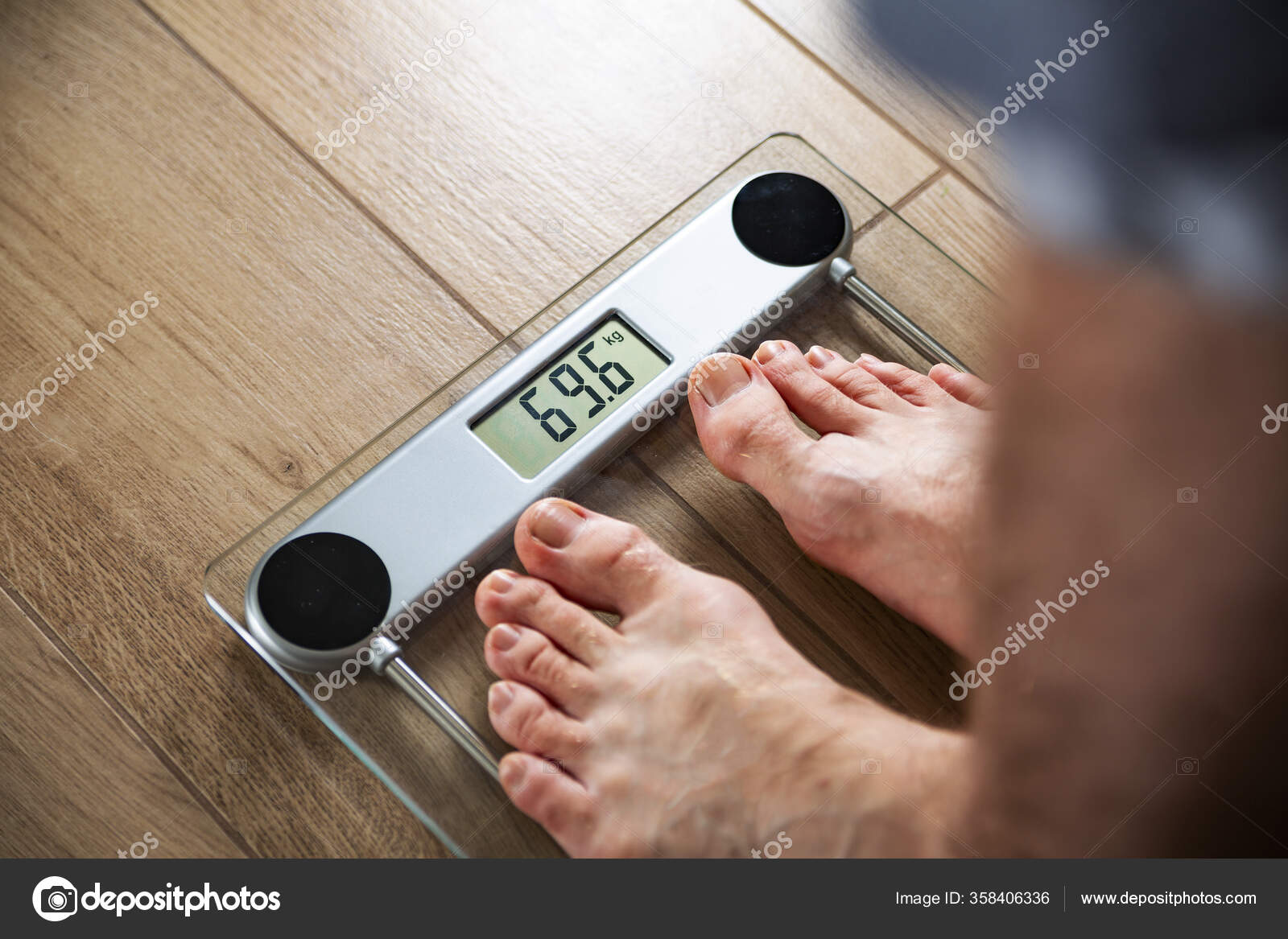 A fit man standing on an electronic household scale in a bathroom
