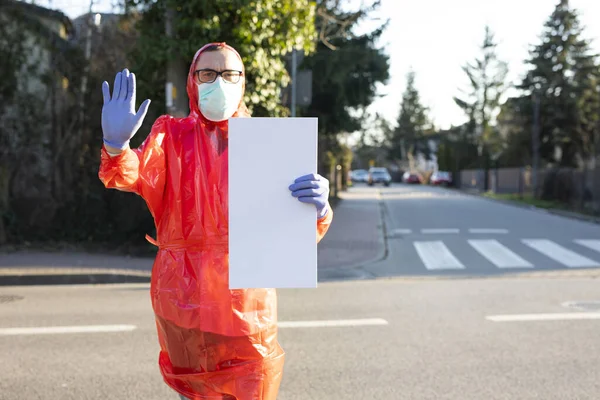 一个穿着防护服 戴着手套 戴着外科口罩的男人 在阳光明媚的大街上拿着一块带有复制空间的空白板 阻止来自中国武汉的Sars病毒大流行 — 图库照片
