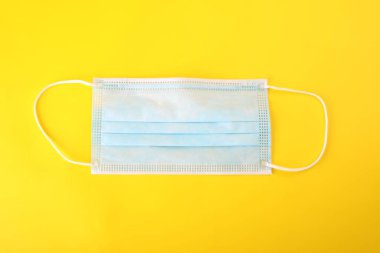 Sarı arka planda tek kullanımlık steril cerrahi maske. Tıbbi şeyler. Koruma kiti. Coronavirus SARS, COVID-19 salgınına karşı mücadele.