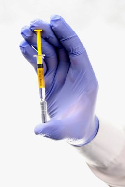 Aşı. Mavi, nitrili, tek kullanımlık koruyucu eldivenli bir doktor elinde aşı olan bir şırınga tutuyor. Viral hastalıklara ve virüslere karşı önleyici aşılar. Koronavirüs salgınını durduruyorum..