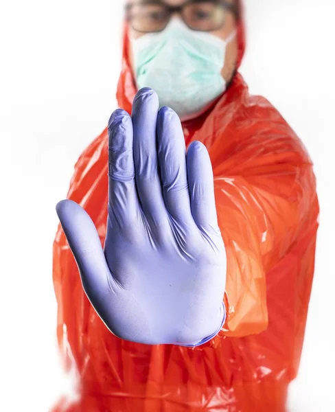 Vertical view of a stay away hand gesture, made by man in a protective suit, single use mask and gloves on white background. Protection against coronavirus infection. Fighting with pandemic from China