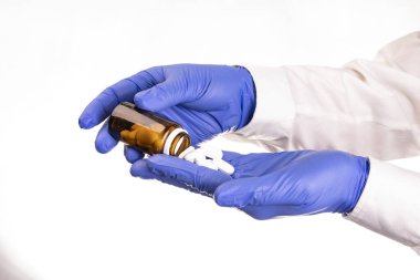 Tıp çalışanı, eczacı elleri, mavi, azot koruyucu eldivenler, beyaz arka planda paketten bir ele hapları çıkarmak. Eczacılık firması. İlaçlar pakette. Hastalık tedavisi.