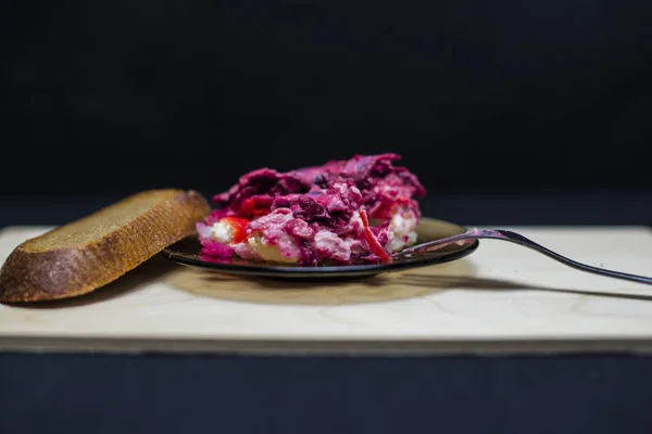 Sebze salatası, siyah arka planda bir tabakta.