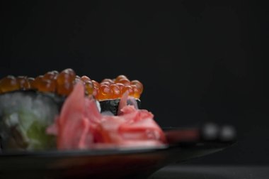 Japon yemeği suşisi koyu bir arka planda yuvarlanıyor.