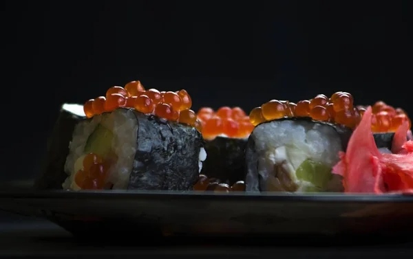Japon yemeği suşisi koyu bir arka planda yuvarlanıyor.