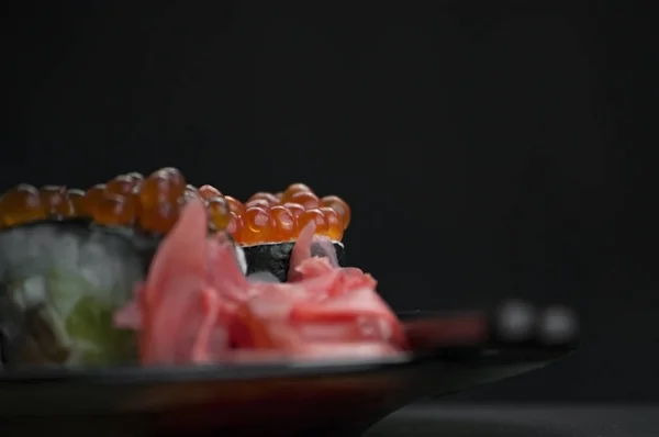 Japon yemeği suşisi koyu bir arka planda yuvarlanıyor.