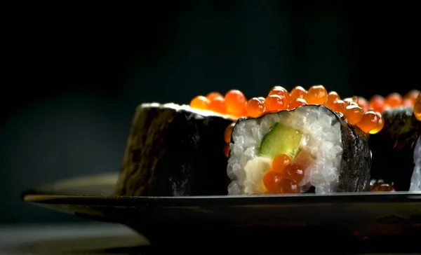 Japon yemeği suşisi koyu bir arka planda yuvarlanıyor.