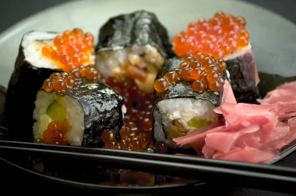 Japon yemeği suşisi koyu bir arka planda yuvarlanıyor.