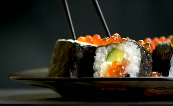 Japon yemeği suşisi koyu bir arka planda yuvarlanıyor.