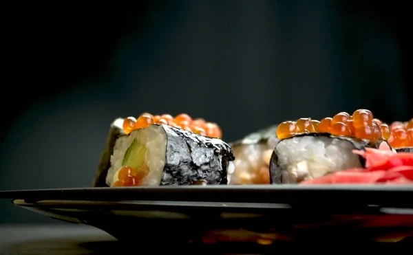 Japon yemeği suşisi koyu bir arka planda yuvarlanıyor.