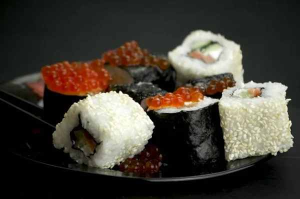 Japon yemeği suşisi koyu bir arka planda yuvarlanıyor.