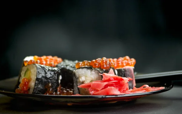 Japon yemeği suşisi koyu bir arka planda yuvarlanıyor.
