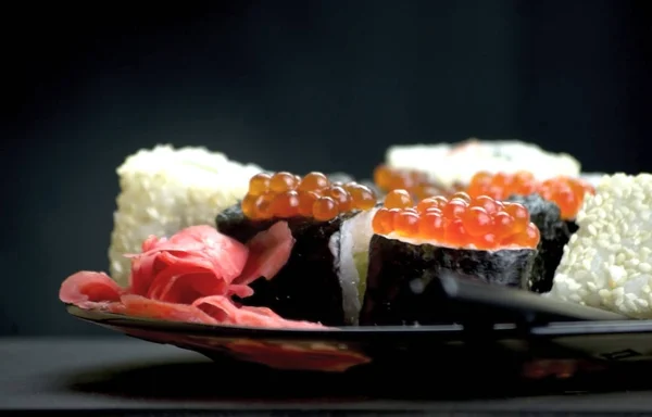 Japon yemeği suşisi koyu bir arka planda yuvarlanıyor.