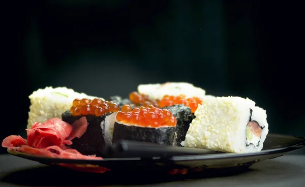 Japon yemeği suşisi koyu bir arka planda yuvarlanıyor.