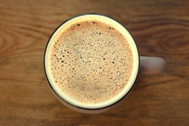 Kahverengi ahşap arka planda güzel köpüklü bir fincan kahve. Sıcak renkler, şık tonlama..