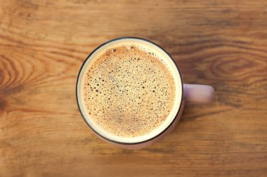 Kahverengi ahşap arka planda güzel köpüklü bir fincan kahve. Sıcak renkler, şık tonlama..