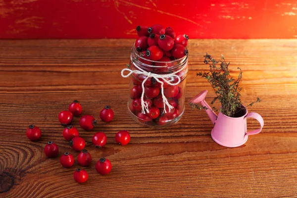 Immunity boosting treatments, infusions. Natural thyme, mint herbs and rosehip berries in a jar on a wooden background. — Stock Photo, Image