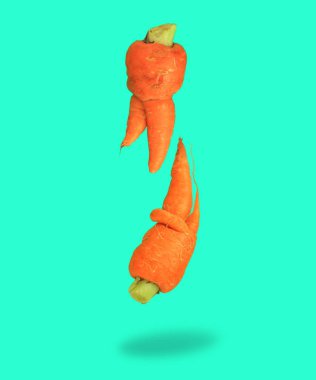 Çirkin yemek. Moda olan su turkuaz arka planda deforme olmuş havuçlar. Yiyecek atığı kavramı. Minimum yassılaşma, pop sanat tarzı.