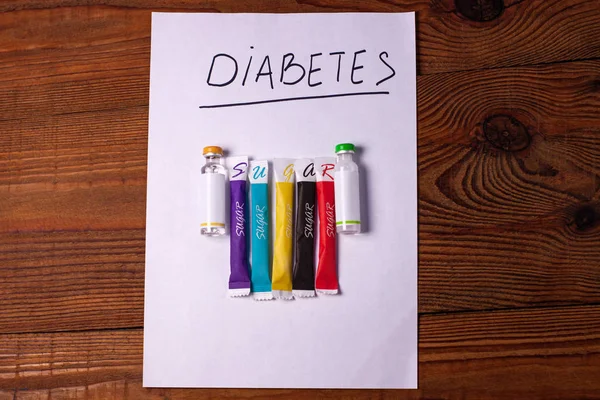 Diabetes tanda pada kertas putih dengan ampul insulin, gula tongkat pada latar belakang kayu, pencegahan penyakit, deteksi . — Stok Foto