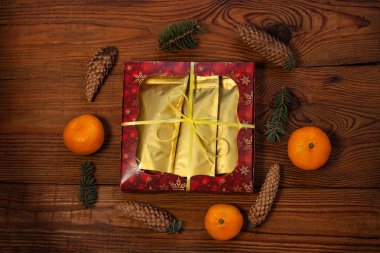 Altın çanta içinde noel hediyesi, kırmızı hediye kutusu, kırsal ahşap arka planda yeni yıl süslemeleri ile sarılı, düz yatak.