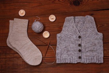 Sıcak, düz bir yatak. Kış konsepti Düz örgü süveter, mumlar, iğneler ve ahşap arka planda iplik. Sıcak hafta sonu.