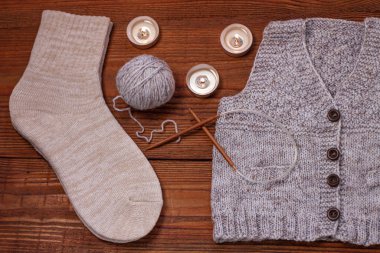 Sıcak, düz bir yatak. Kış konsepti Düz örgü süveter, mumlar, iğneler ve ahşap arka planda iplik. Sıcak hafta sonu.