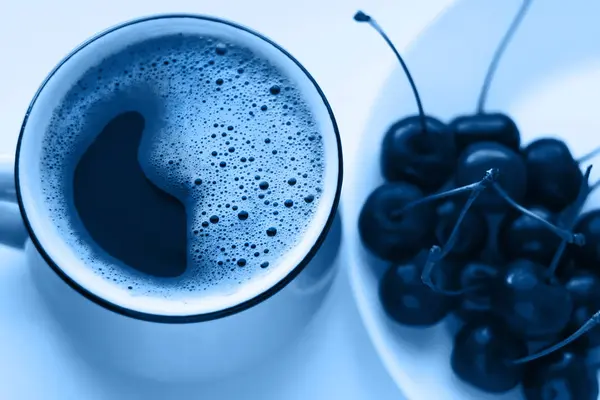 Café e cerejas na moda tonificação azul, conceito de comida minimalista. Saboreie frutas cereja em um prato branco, papel de parede — Fotografia de Stock