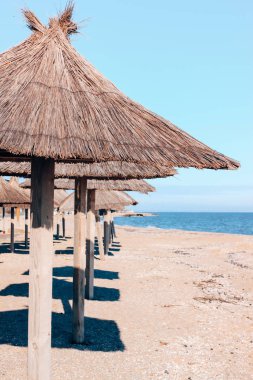 Hasır şemsiye, mavi deniz suyu ve gökyüzü arka planı. Güney sahili manzaralı duvar kağıdı, yaz tatili konsepti.