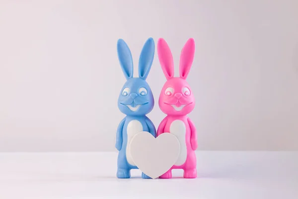 Niedliche Hasen als glückliches Liebespaar mit weißem Herz auf hellem Hintergrund, kreative Valentinstagskarte. Minimaler Stil. — Stockfoto