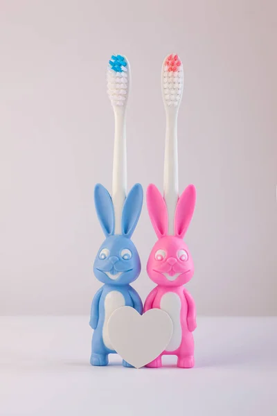 Escovas de dentes infantis em uma forma de coelhos bonitos em um fundo branco isolado. Dois coelhos com coração em branco . — Fotografia de Stock