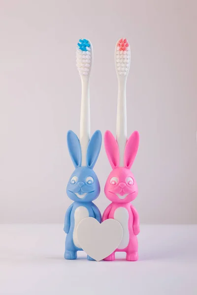 Children's toothbrushes in a form of cute bunnies on a white background isolated. Two rabbits with blank heart. — Stock Photo, Image